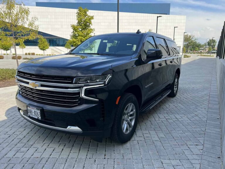Front three-quarter view of a black Contact Limo Chevy Suburban on a paved forecourt