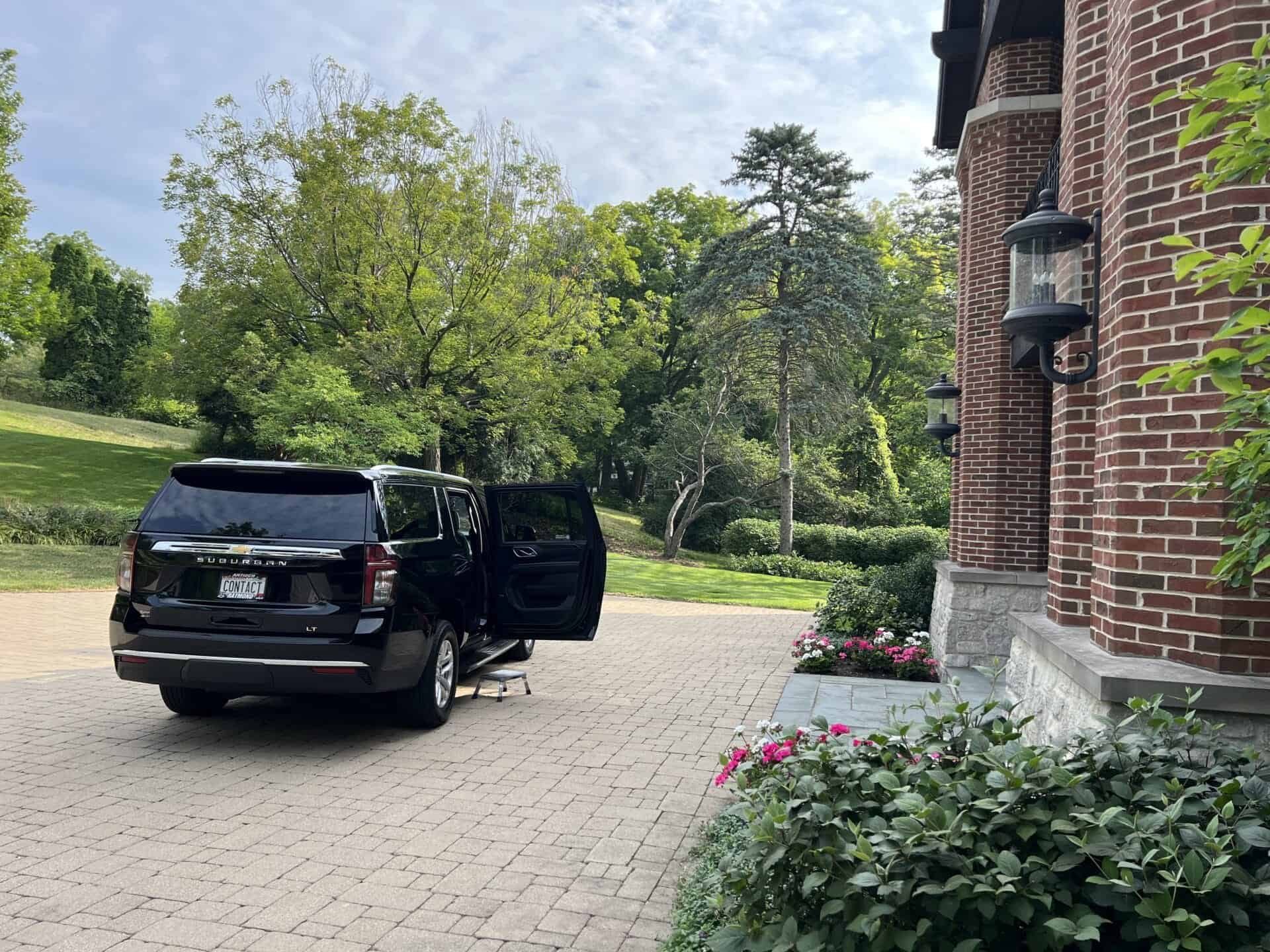 Black luxury SUV waiting with the door open at a residential pickup